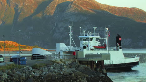 Video-of-a-moving-boat-in-the-foreground,-and-coastal-mountains-painted-by-sunlight-in-the-background