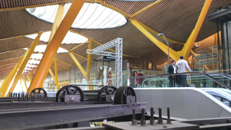 Panoramic-shot-of-two-friends-taking-a-escalator-inside-a-terminal-of-Madrid-airport