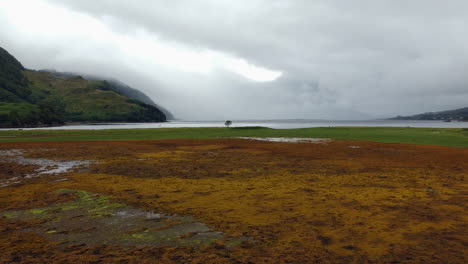 Tiro-De-Drone-Largo-Del-Lago-De-Las-Tierras-Altas-Escocesas-En-Un-Día-Nublado-Y-Cambiante