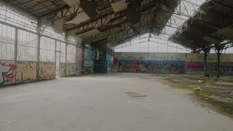 Vista-POV-Desde-El-Interior-De-Un-Almacén-Abandonado-Con-Graffiti-En-Las-Paredes.
