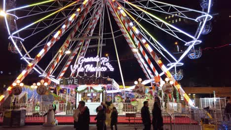 Medium-wide-slow-motion-dolly-pan-shot-of-the-giant-Ferris-Wheel-on-Monte-Carlo's-Christmas-market-at-Port-Hercule,-Rue-de-la-Piscine