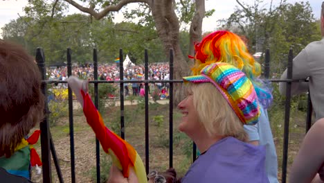 Elderly-lady-with-hat-and-rainbow-flag-speaks-and-celebrates-the-gay-pride