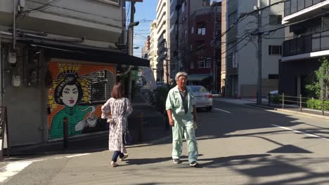 Menschen,-Die-Die-Straße-In-Osaka,-Japan,-Vor-Einer-Graffitiwand-Entlang-Wackeln
