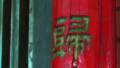 Chinesische-Schriftzeichen-Zieren-Einen-Leuchtend-Roten-Hölzernen-Türpfosten,-Der-Nach-Unten-Geneigt-Ist