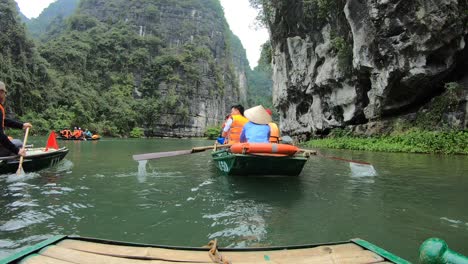 Row-boats-Ninh-Binh-Vietnam,-tourists-travelling-Ngo-Dong-River-and-caves