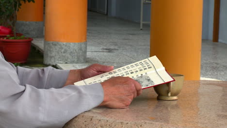 Hands-of-man-holding-book-with-orange-columns-in-background