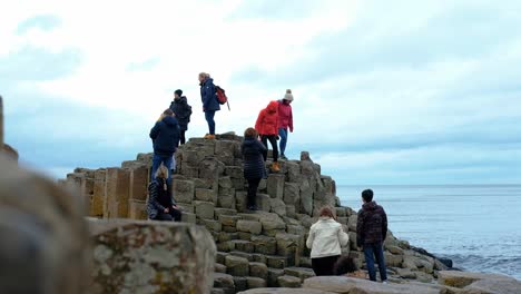 Group-of-tourists-climbing-on-Irish-Giants-causeway-coastal-tourist-attraction,-Northern-Ireland