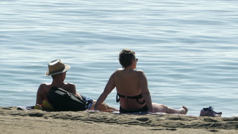 Couple-Laying-on-the-Beach-in-the-Sun,-Sea-Background