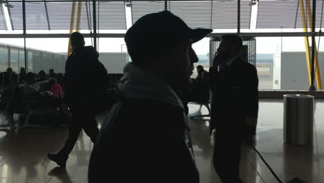 Reiseaufnahme-Von-Der-Seite-Der-Silhouetten-Von-Menschen,-Die-In-Zeitlupe-Auf-Einem-Terminal-Des-Flughafens-Madrid-Warten