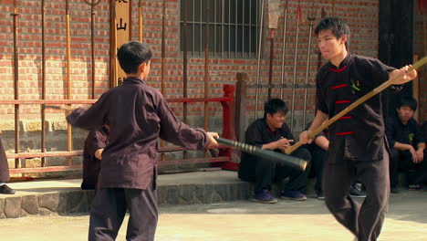 Estudiante-De-Artes-Marciales-Practicando-La-Pelea-Con-Palos-De-Sensei.