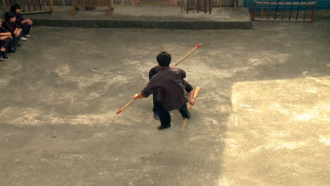 Young-Chinese-men-demonstrate-and-perform-stick-fighting-in-courtyard