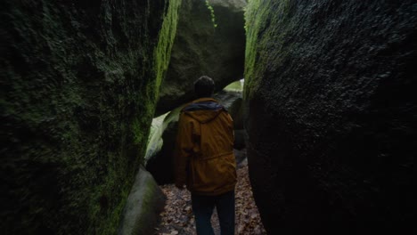 Adult-Male-Exploring-In-Between-Large-Moss-Covered-Boulders