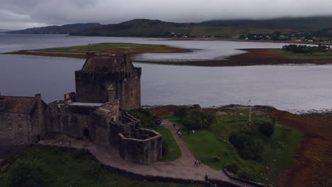 Eilean-Donan-Castle-Drohnenaufnahme-Bei-Sonnenuntergang-An-Einem-Bewölkten,-Launischen-Tag