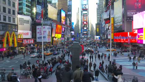 Blick-Von-Einer-Plattform-Auf-Den-Times-Square-Mit-Massen-Von-Touristen,-Die-Fotos-Machen-Und-Auf-Blinkende-Schilder-Und-Werbetafeln-Schauen,-Die-Diesen-Ort-Zu-Einer-Beliebten-Touristenattraktion-Machen