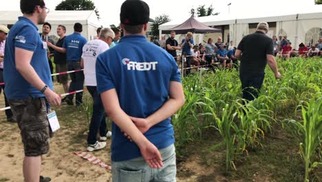 Voluntarios-De-Agrotecnología-Probando-Tractores-Controlados-Remotamente-En-Un-Campo-De-Hierba-En-Alemania,-Plano-Medio.