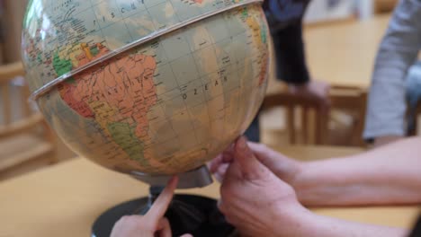 Teacher-rotating-the-world-globe-while-showing-it-to-kids-at-elementary-school