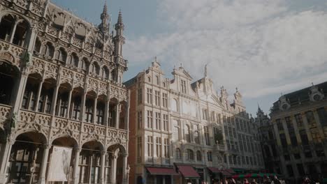 Gente-Caminando-En-La-Plaza-Grote-Markt,-Piedra-Iluminada-Por-El-Sol,-Altos-Edificios-Antiguos