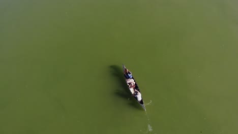 Top-view-of-two-rowing-men-in-a-wooden-canoe-paddling-upstream-on-the-river
