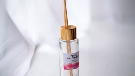 Wooden-sticks-are-put-into-a-lemon-reed-diffuser,-White-background