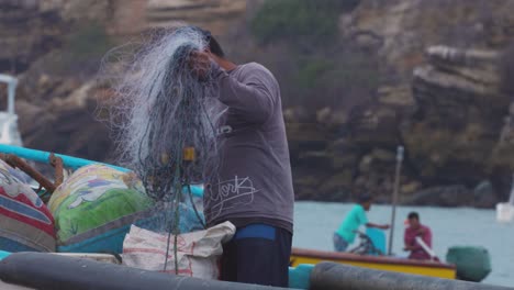 Pescador-Recogiendo-Una-Red-De-Pesca-En-Un-Barco-Ubicado-En-Ecuador