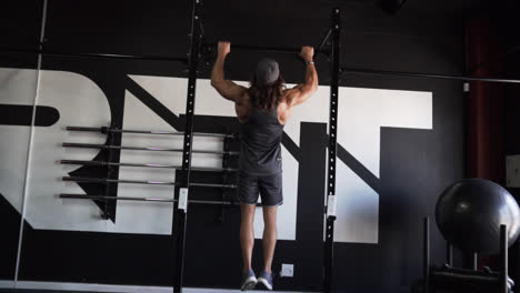 Hombre-Musculoso-Con-Pelo-Largo-Haciendo-Flexiones-En-Un-Gimnasio-Oscuro-Con-Movimiento-De-Cámara