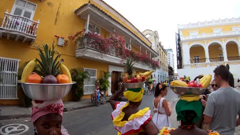 Palenqueras-in-Cartagena-are-wearing-colorful-dresses-and-balancing-fruits-bowls-in-their-heads