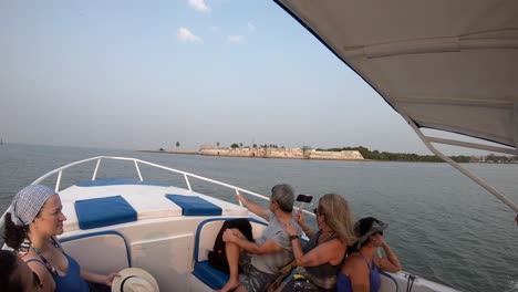 Tourists-on-a-moving-boat-are-recording-with-their-cameras-the-ocean-and-island-close-to-Cartagena-de-Indias,-Colombia