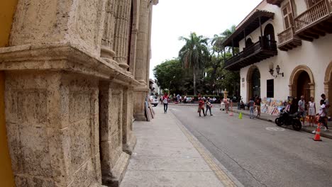 En-Una-Calle-Del-Casco-Antiguo-De-Cartagena-De-Indias,-Varias-Personas-Pasan-Caminando.