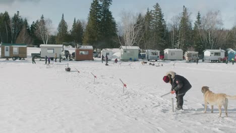 Pequeñas-Cabañas-De-Hielo-En-El-Lago-Blanco-Congelado-Megantic-En-Quebec-Con-Gente-Con-Perro