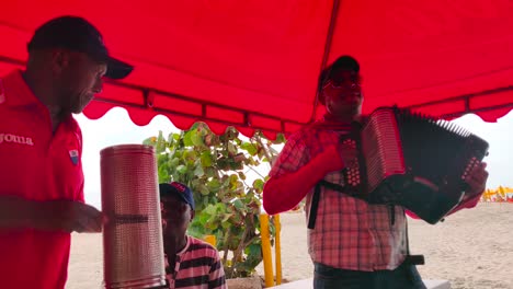 A-man-is-playing-the-accordion-along-with-his-fellow-band-members-who-play-the-Guacharaca-and-the-caja