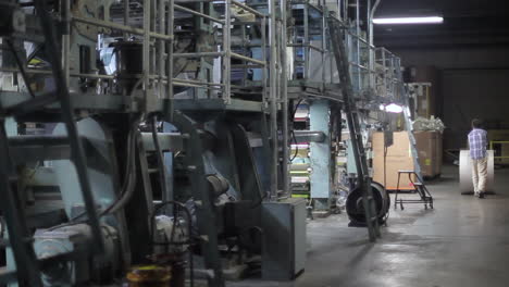 Worker-walking-with-a-big-roll-of-paper-in-newspaper-factory