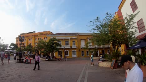 Los-Turistas-Caminan-En-Una-Gran-Plaza-Con-Coloridas-Casas-Y-Edificios-Del-Casco-Antiguo-De-Cartagena-De-Indias,-Colombia.