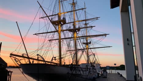The-historic-ship-HMS-Jarramas-standing-at-the-dock-at-sunset-with-a-beautiful-pink-and-blue-sunset-sky,-in-the-naval-city-Karlskrona-in-the-southern-part-of-Sweden