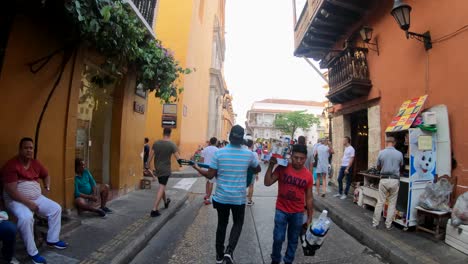 Un-Hombre-Camina-Mientras-Toca-La-Guitarra-En-La-Calle-Del-Casco-Antiguo-De-Cartagena-De-Indias,-Colombia