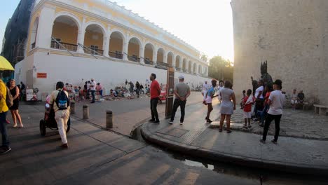 Local-people-and-tourists-are-standing-and-walking-in-a-plaza-and-street-of-the-old-town-of-Cartagena-de-Indias,-Colombia