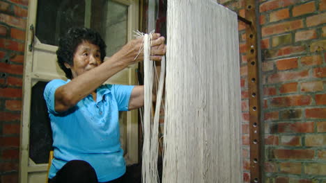 Woman-gathers-noodles-and-folds-into-bundles-to-prepare-to-package-for-sale