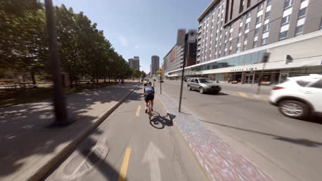 POV-Hinter-Radfahrern-Entlang-Der-Sonnigen-Berri-Street-In-Montreal,-Kanada