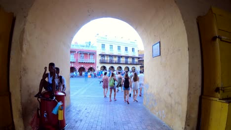 Several-women-are-walking-down-an-arc-entering-a-plaza-of-the-old-town-of-Cartagena-de-Indias,-Colombia