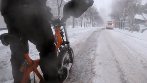 Zeitraffer-Seitenwinkelperspektive-Eines-Kuriers-Auf-Einem-E-Bike,-Der-Durch-Einen-Schneesturm-In-Der-Innenstadt-Von-Montreal-Fährt
