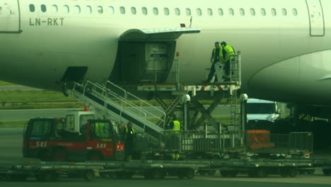 Trabajadores-Del-Aeropuerto-Con-Chaquetas-Reflectantes-Amarillas-Cargando-Un-Avión-De-Carga