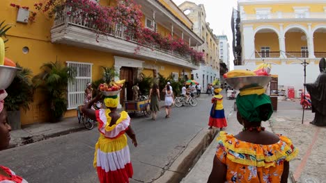 4-palenqueras-with-colorful-dresses-are-balancing-fruit-bowls-on-their-head-in-the-old-town-of-Cartagena-de-Indias,-Colombia