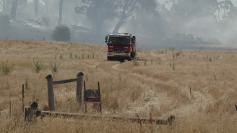 Fire-truck-travelling-through-farm-land-with-grass-fire-extinguished-in-the-background