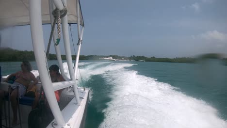 Two-tourists-are-sitting-on-a-boat-with-a-sunroof-while-the-boat-moves-on-the-ocean-and-creates-waves-and-splashes-water