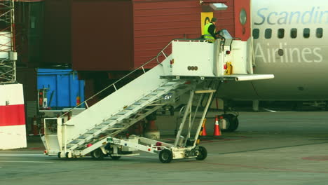 Flughafenarbeiter-Fährt-Mobile-Flugtreppe-Neben-Flugzeug,-Das-Am-Gate-Geparkt-Ist