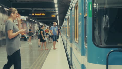 Ankommender-U-Bahn-Zug-Mit-Menschen,-Die-Auf-Dem-Bahnsteig-Darauf-Warten,-Für-Den-Transfer-Zu-Ihrem-Ziel-Einzusteigen