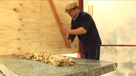Worker-Processing-Paper-Pulp-with-Wooden-Stick,-Old-Papermaking-Process