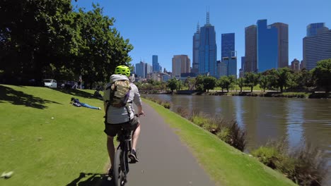 Following-a-cyclist-heading-along-river-bike-path-next-to-river