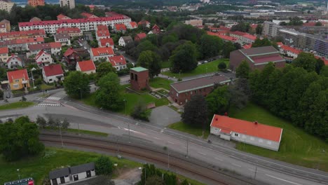 Aerial-view-of-Harlanda-church-in-Bagaregarden,-in-east-Gothenburg-in-Sweden,-with-a-suburban-area-around-it-and-different-apartement-buildings-behind-it-on-a-cloudy-day