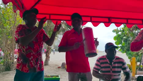 A-band-of-Vallenato-is-playing-Guacharaca,-accordion-and-caja-while-they-sing-and-dance-songs-on-a-beach-of-Cartagena-de-Indias,-Colombia