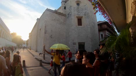 Ein-Führer-Mit-Gelbem-Regenschirm-Führt-Eine-Gruppe-Von-Touristen-Bei-Sonnenuntergang-Durch-Die-Altstadt-Von-Cartagena-De-Indias,-Kolumbien